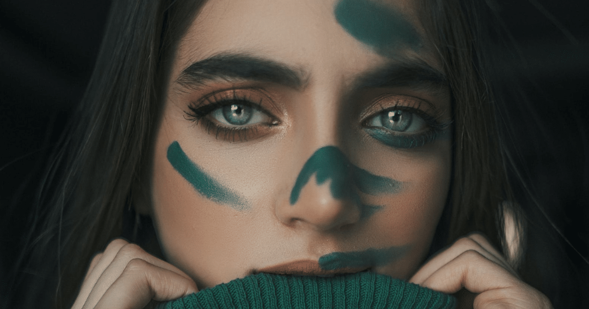 Portrait d'une femme au yeux verts et des tâches de peintures sur le visage 